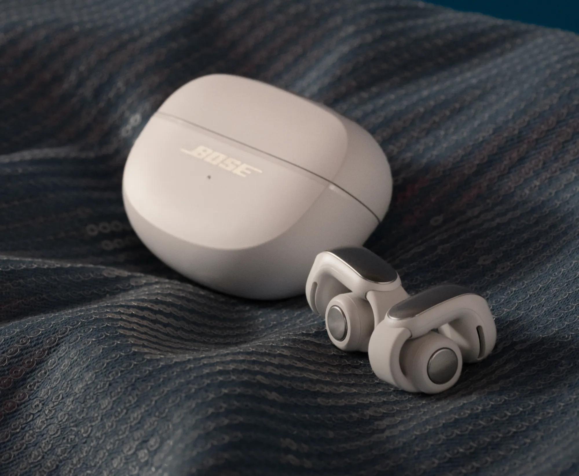 Bose Ultra Open Earbuds and charging case on a blanket.
